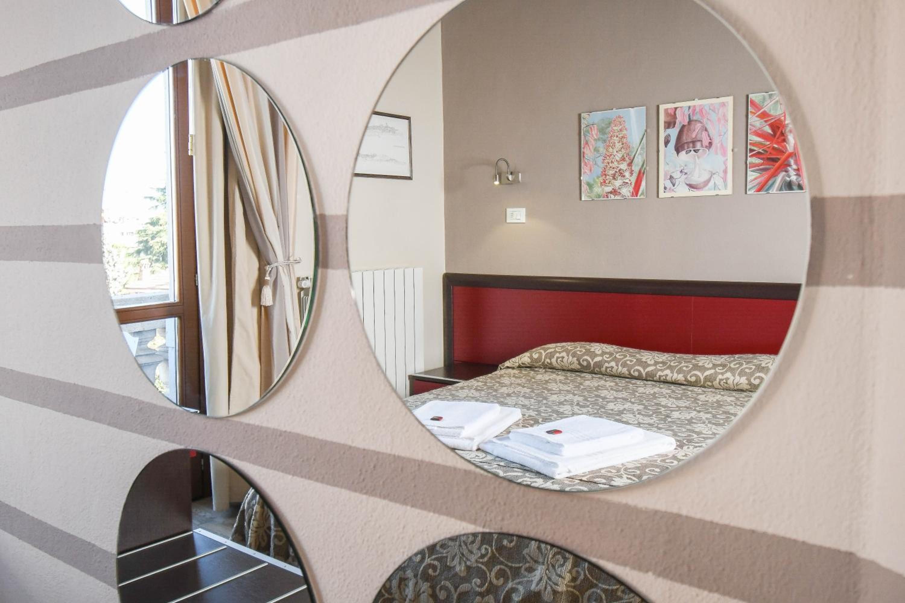 Una habitación de hotel con una cama, una mesita de noche, un espejo y decoración en la pared.
