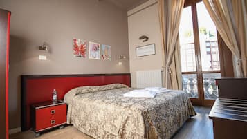A hotel room with a bed, a nightstand, a desk, and a window with curtains.