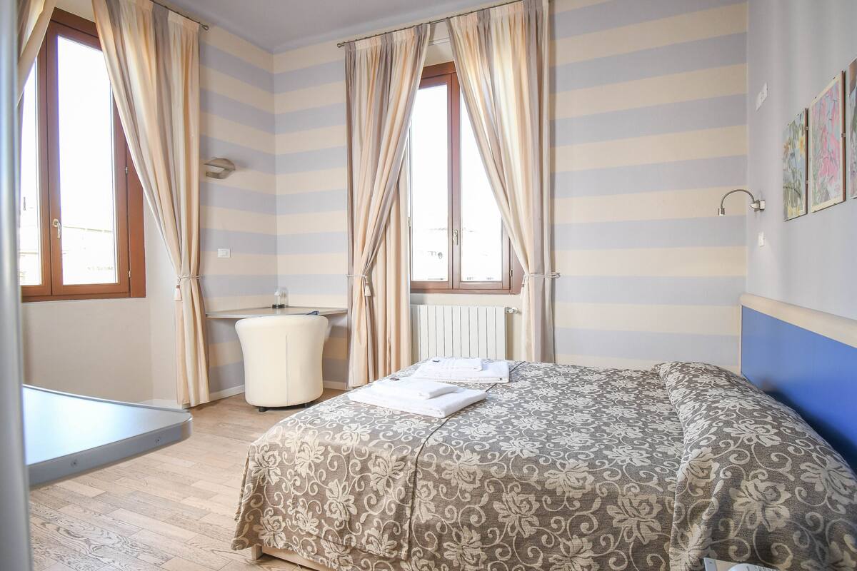 A bedroom with a bed, a window, a radiator, and a bathroom.