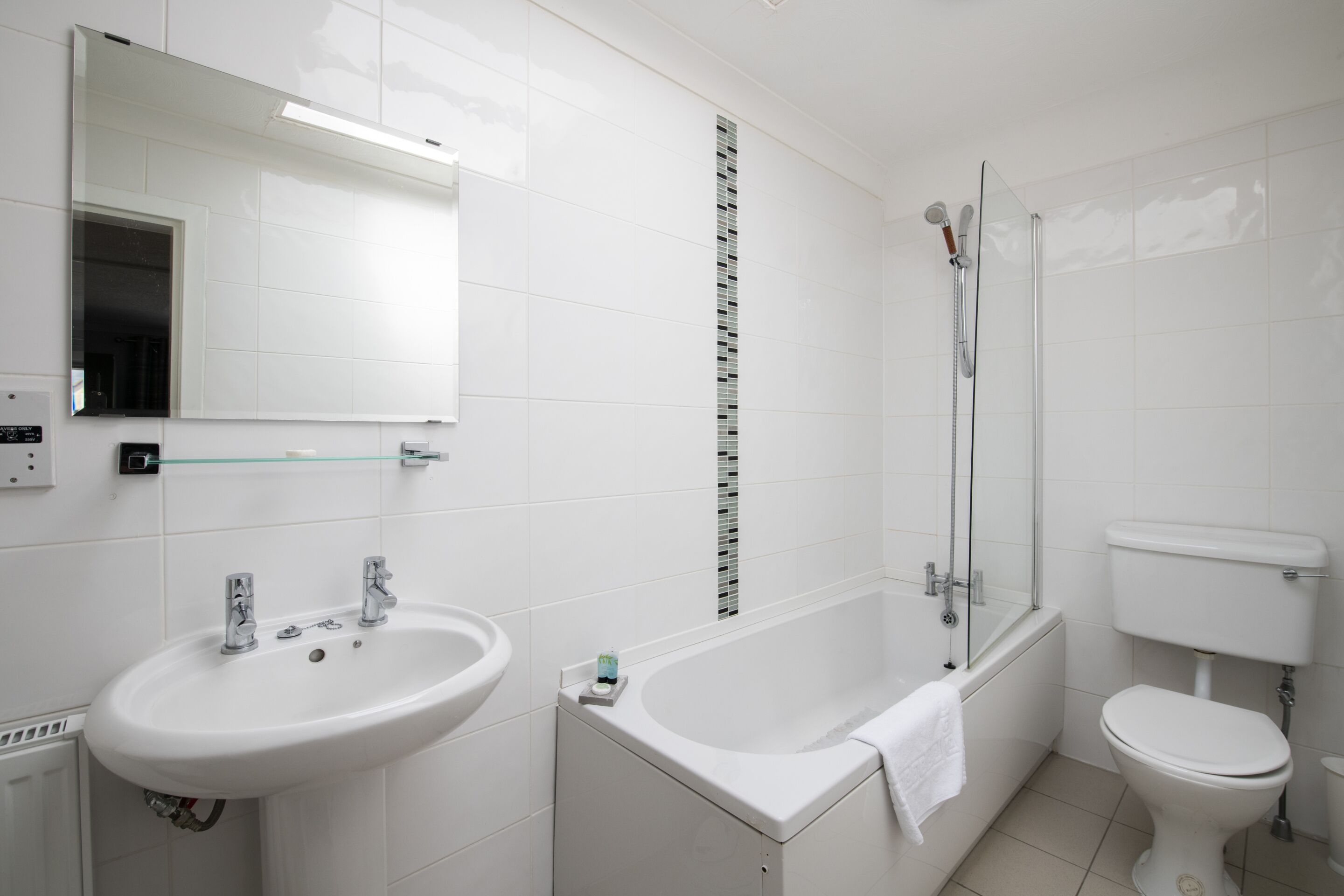 A modern bathroom with a white sink, a bathtub, and a toilet.