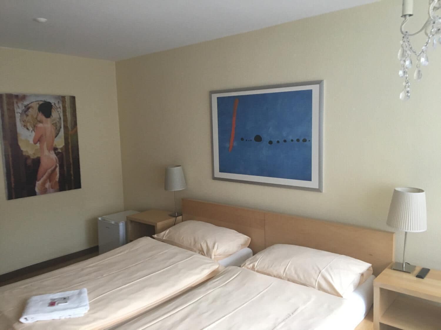 Une chambre d’hôtel avec deux lits, une table de chevet, une lampe et un tableau au mur.