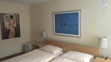 Une chambre d’hôtel avec deux lits, une table de chevet, une lampe et un tableau au mur.
