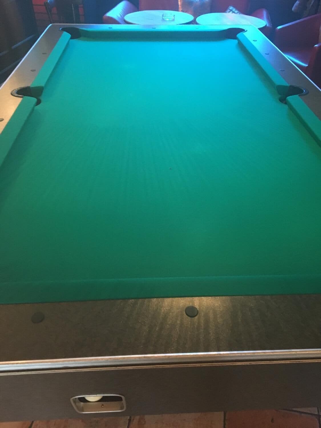 A pool table with a green felt surface and a metal frame.