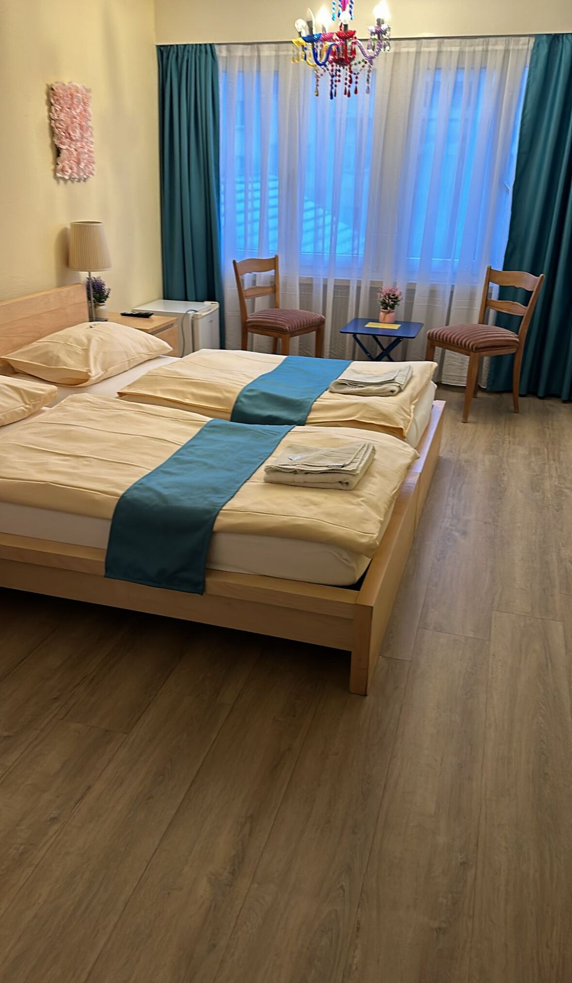Una habitación de hotel con una cama grande, dos sillas, una mesita y un candelabro.