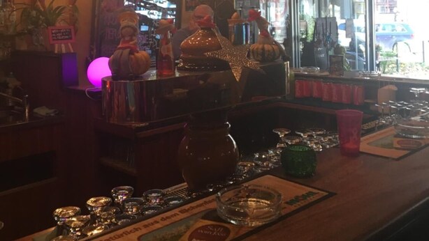 A bar area with a chandelier, a mirror, and various bar items. - Hotel & Backpackers Zak (Neuhausen am Rheinfall)