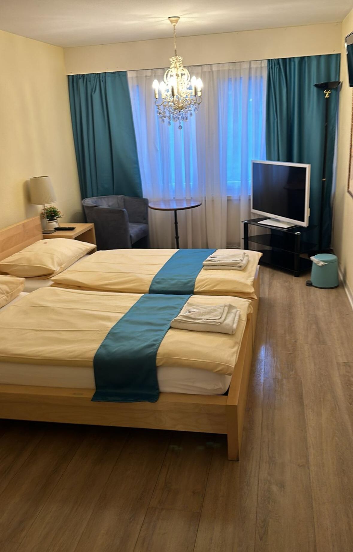 Una habitación de hotel con una cama grande, televisor, escritorio y candelabro.