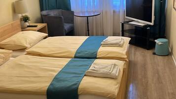 Una habitación de hotel con una cama grande, televisor, escritorio y candelabro.
