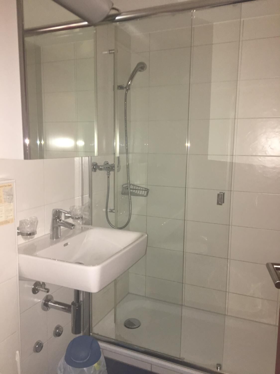 A bathroom with a glass-enclosed shower, a sink, and a mirror.