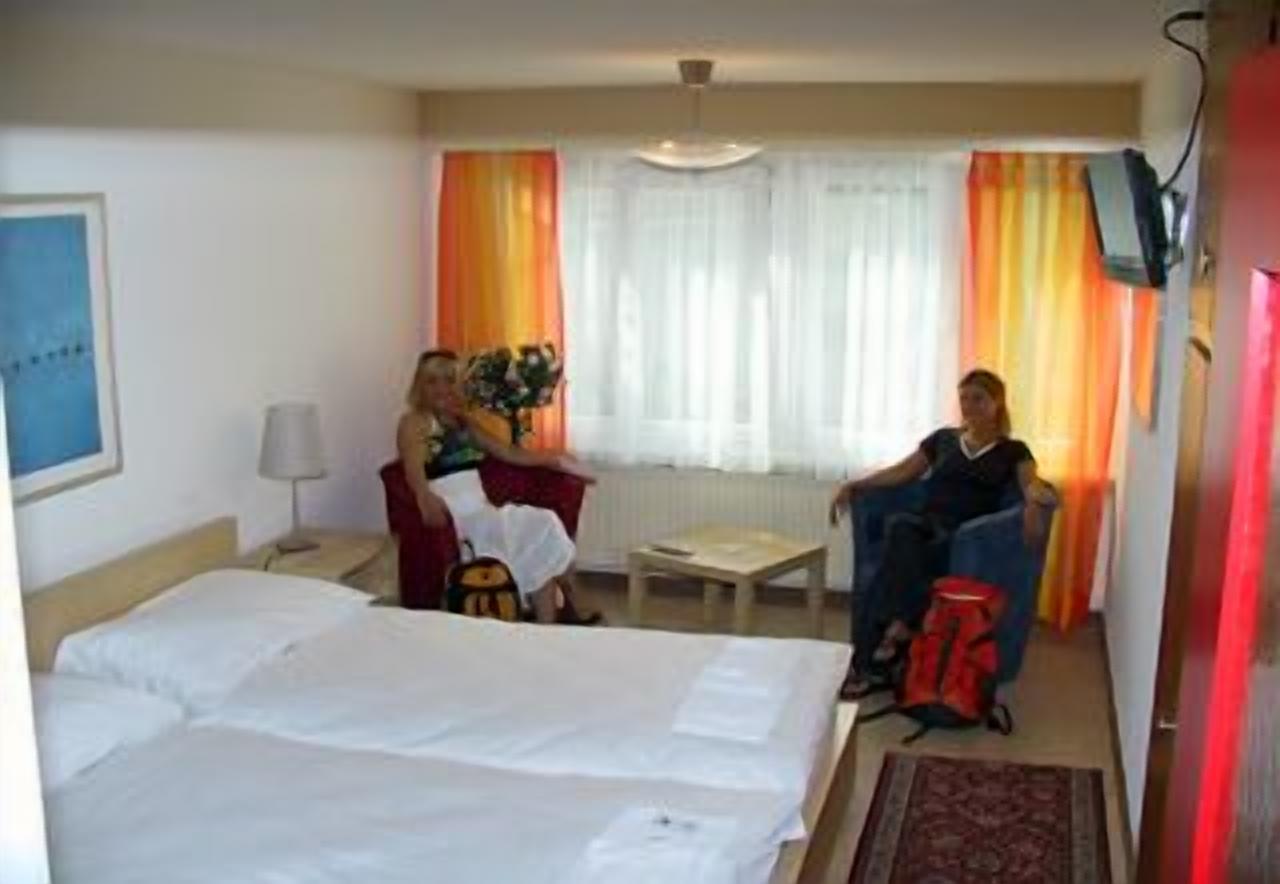 Ein Hotelzimmer mit Bett, Schreibtisch, Stuhl und einem Fenster mit Vorhängen.