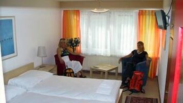 Ein Hotelzimmer mit Bett, Schreibtisch, Stuhl und einem Fenster mit Vorhängen.