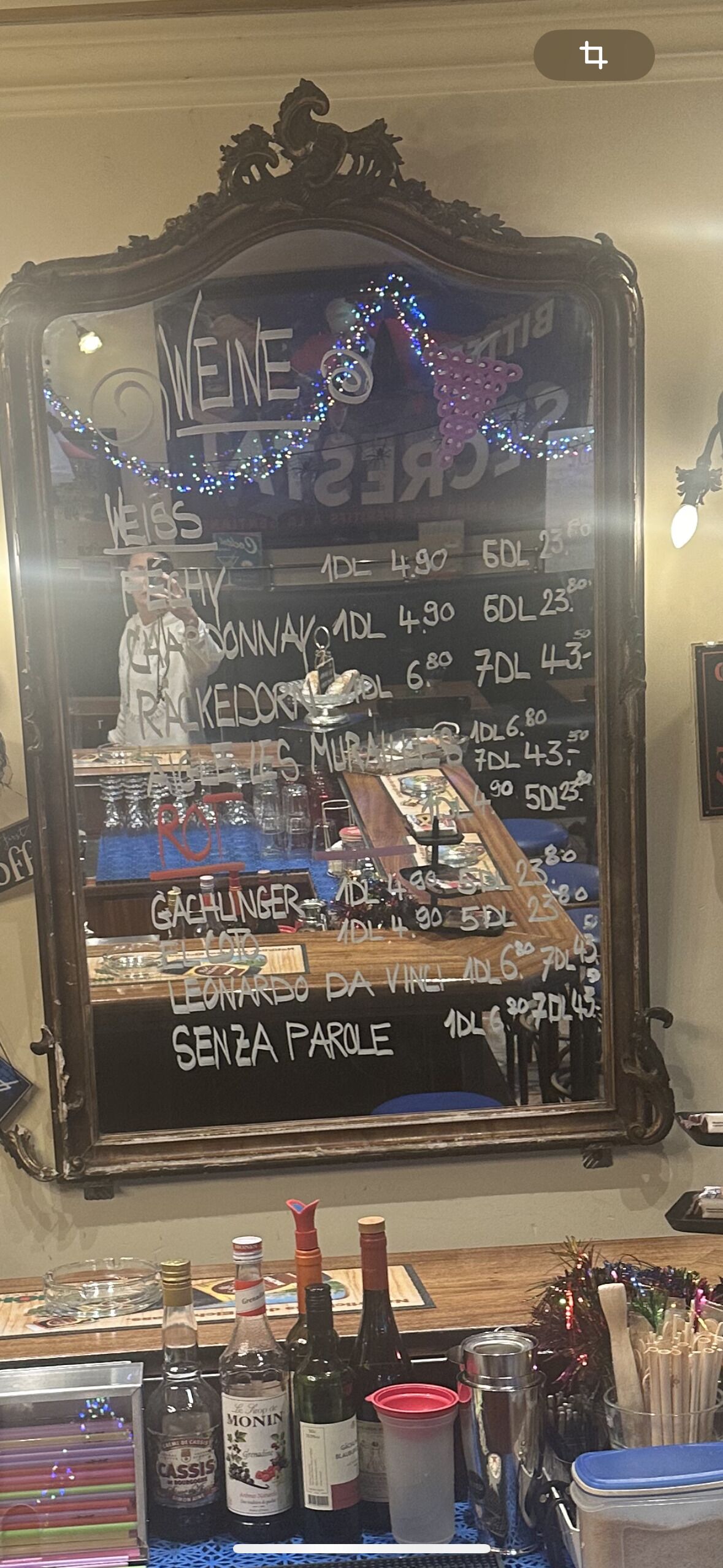 Een spiegel met een krijtbord waarop eten en prijzen staan.