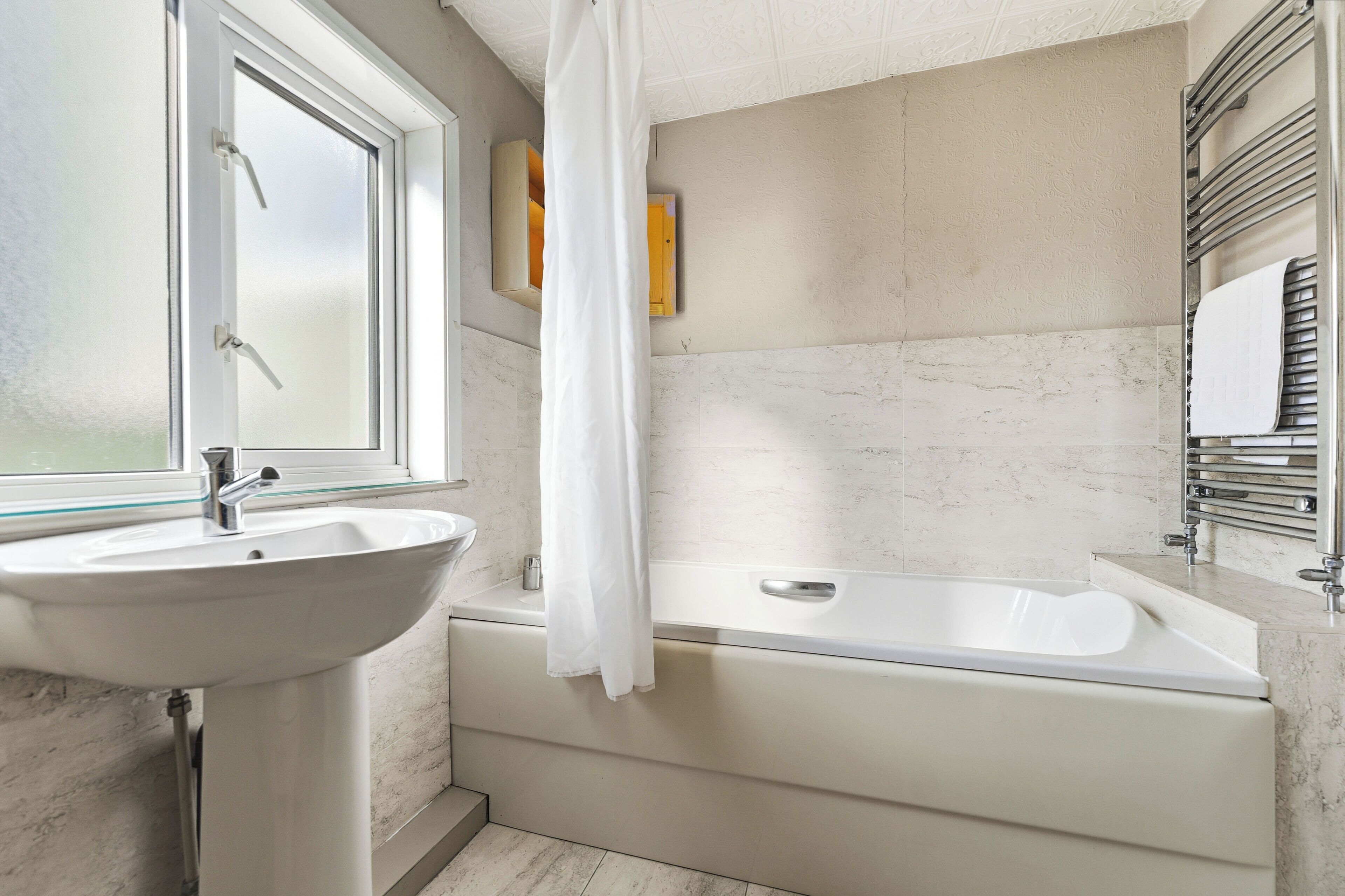 A bathroom with a sink, bathtub, and shower curtain.