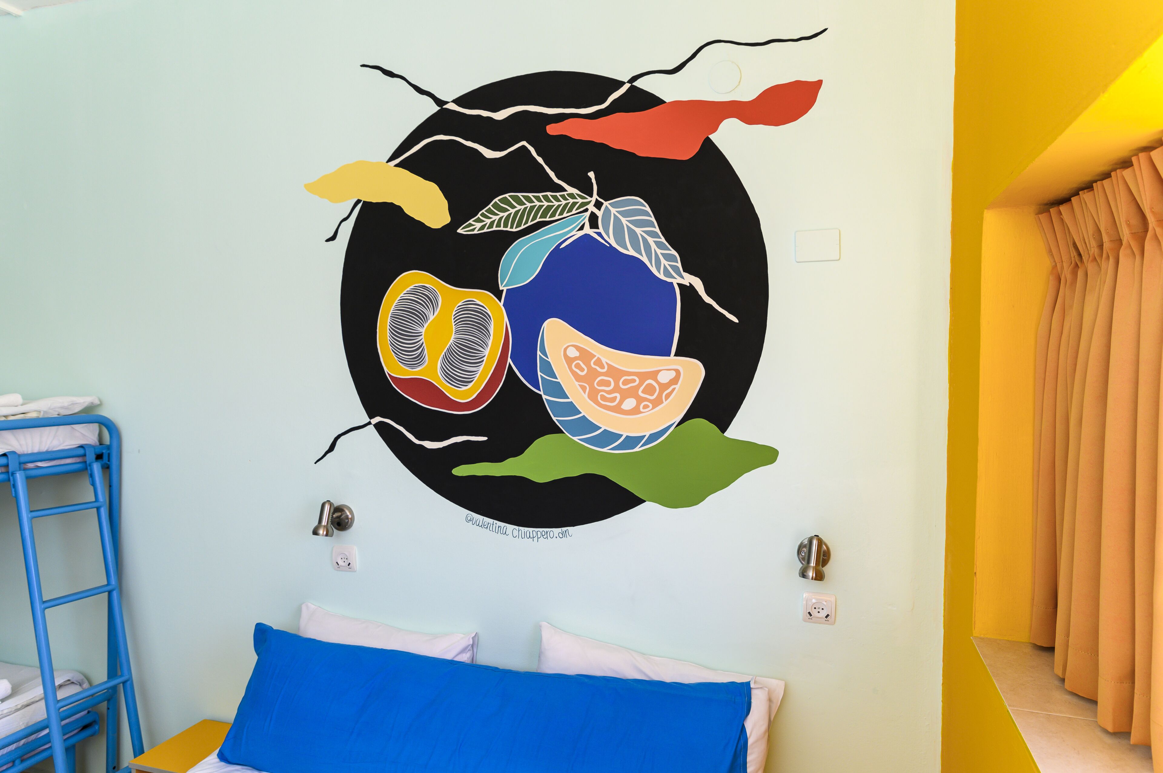 Una habitación con literas, un mural en la pared y una cortina.