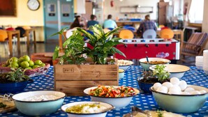 A dining area with a blue polka dot tablecloth, various bowls of food, and a wooden crate with plants. - Abraham Jerusalem  (Jerusalem)