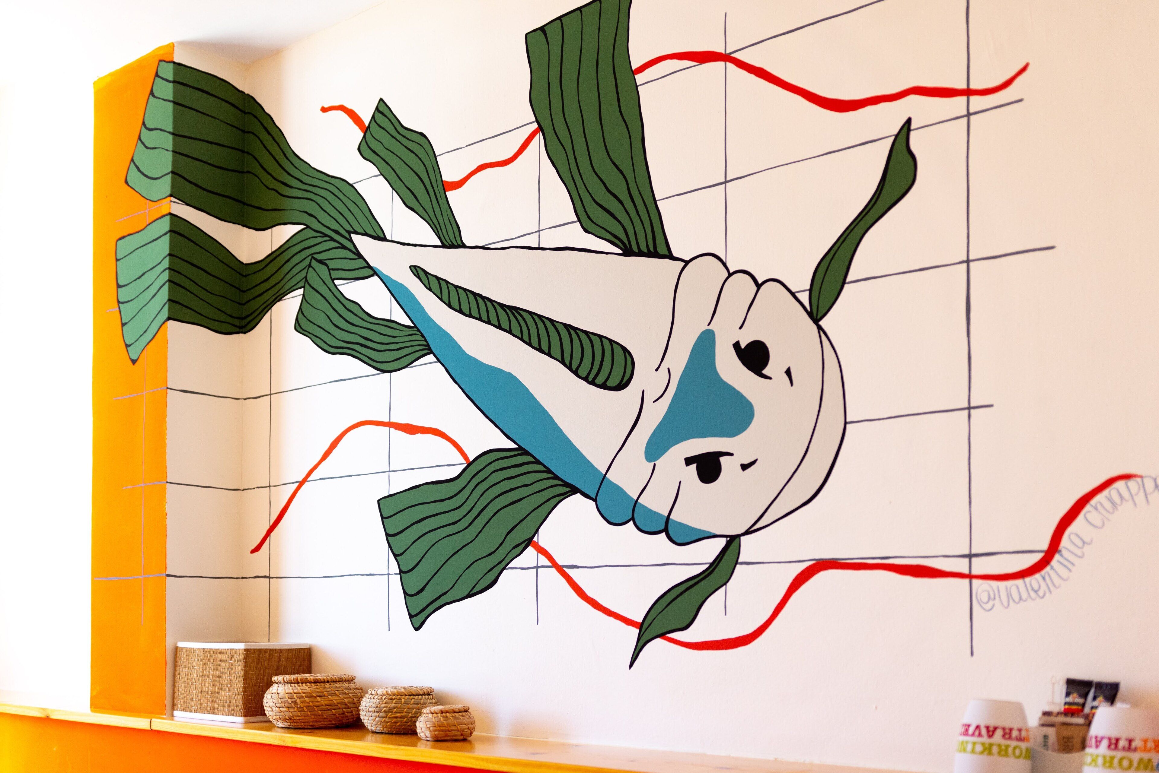 A wall with a large, abstract fish mural.
