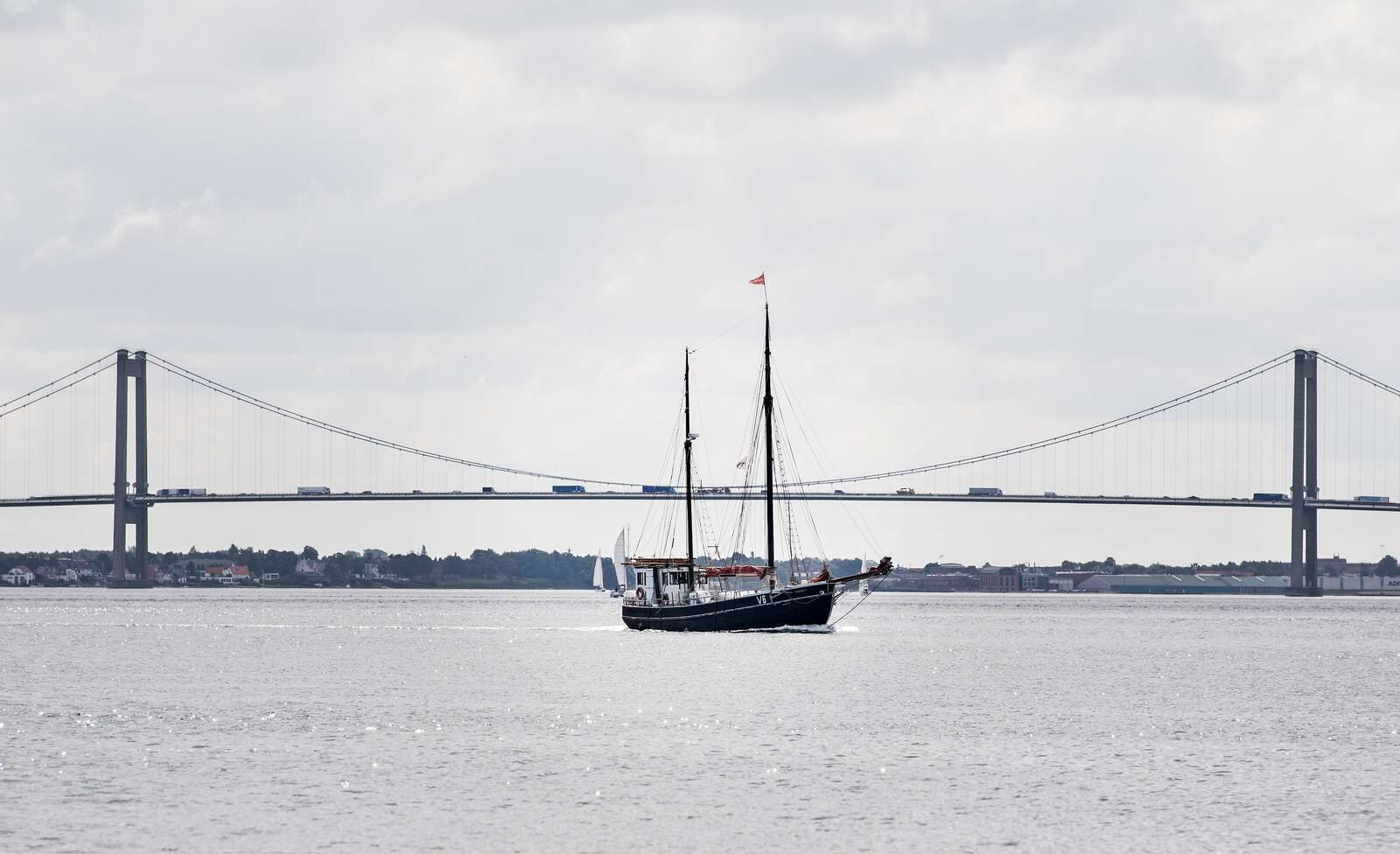 A boat on a river with a bridge in the background.
