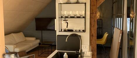 A modern kitchen with a built-in oven, a black faucet, and a shelf with bowls.