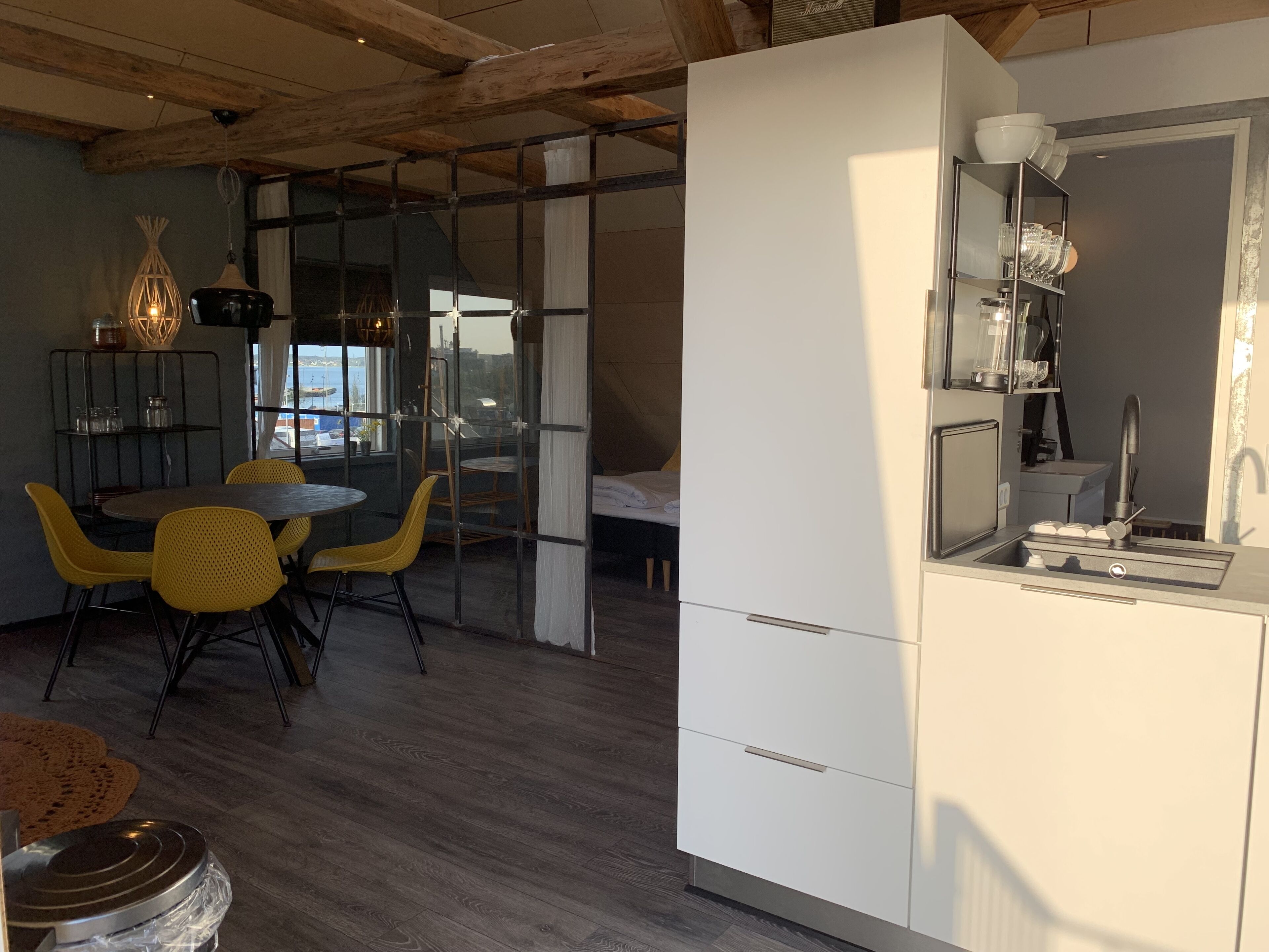 A modern kitchen with white cabinets, a sink, and a dining area with yellow chairs and a round table.