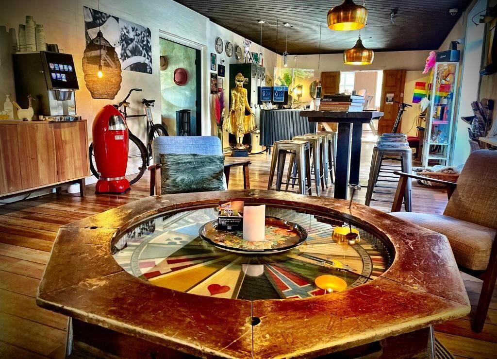 A cozy bar area with a round table, stools, and a red espresso machine.