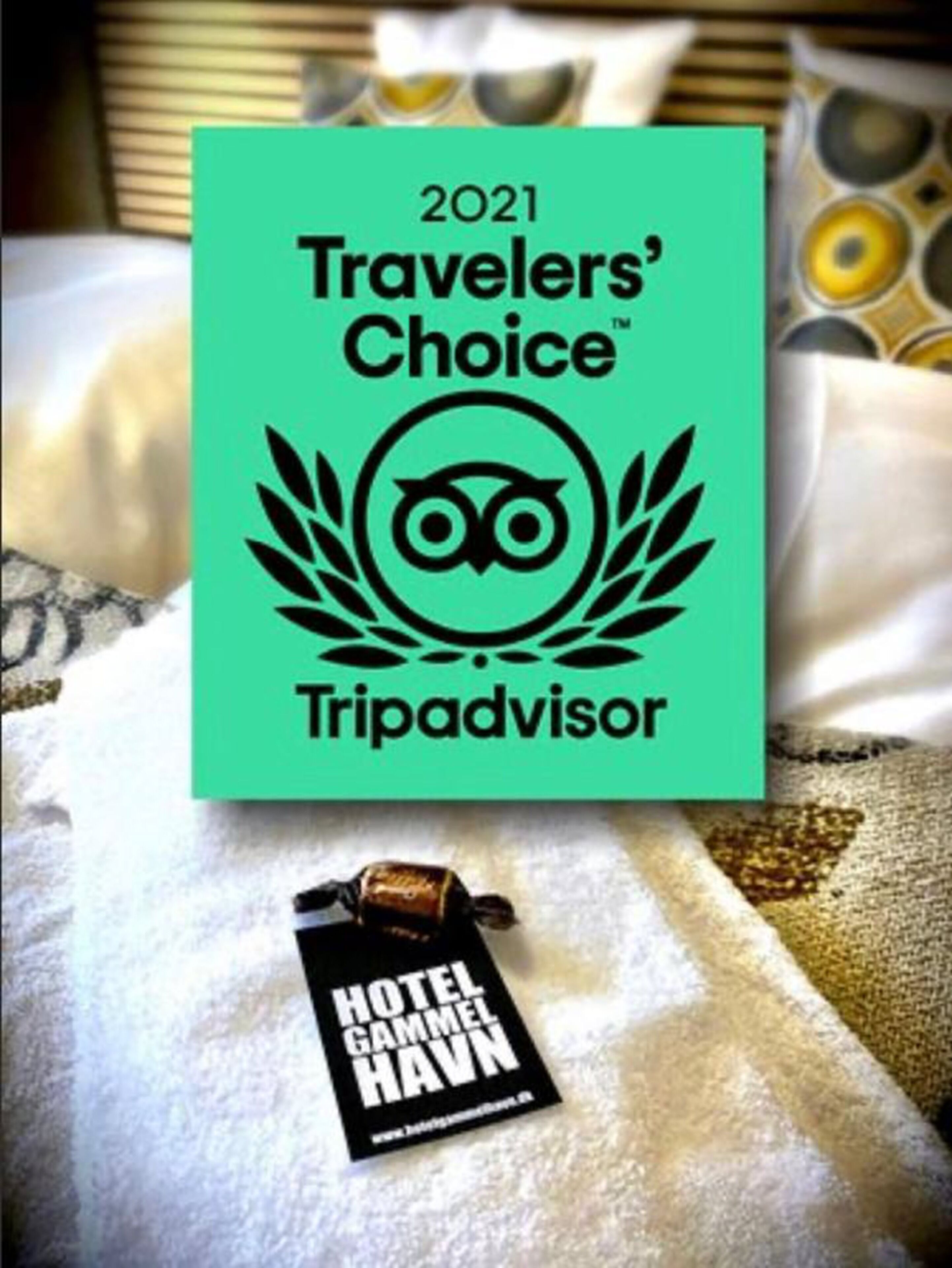 Insignia de premio Travelers’ Choice de Tripadvisor 2021 sobre una cama con una etiqueta de hotel.