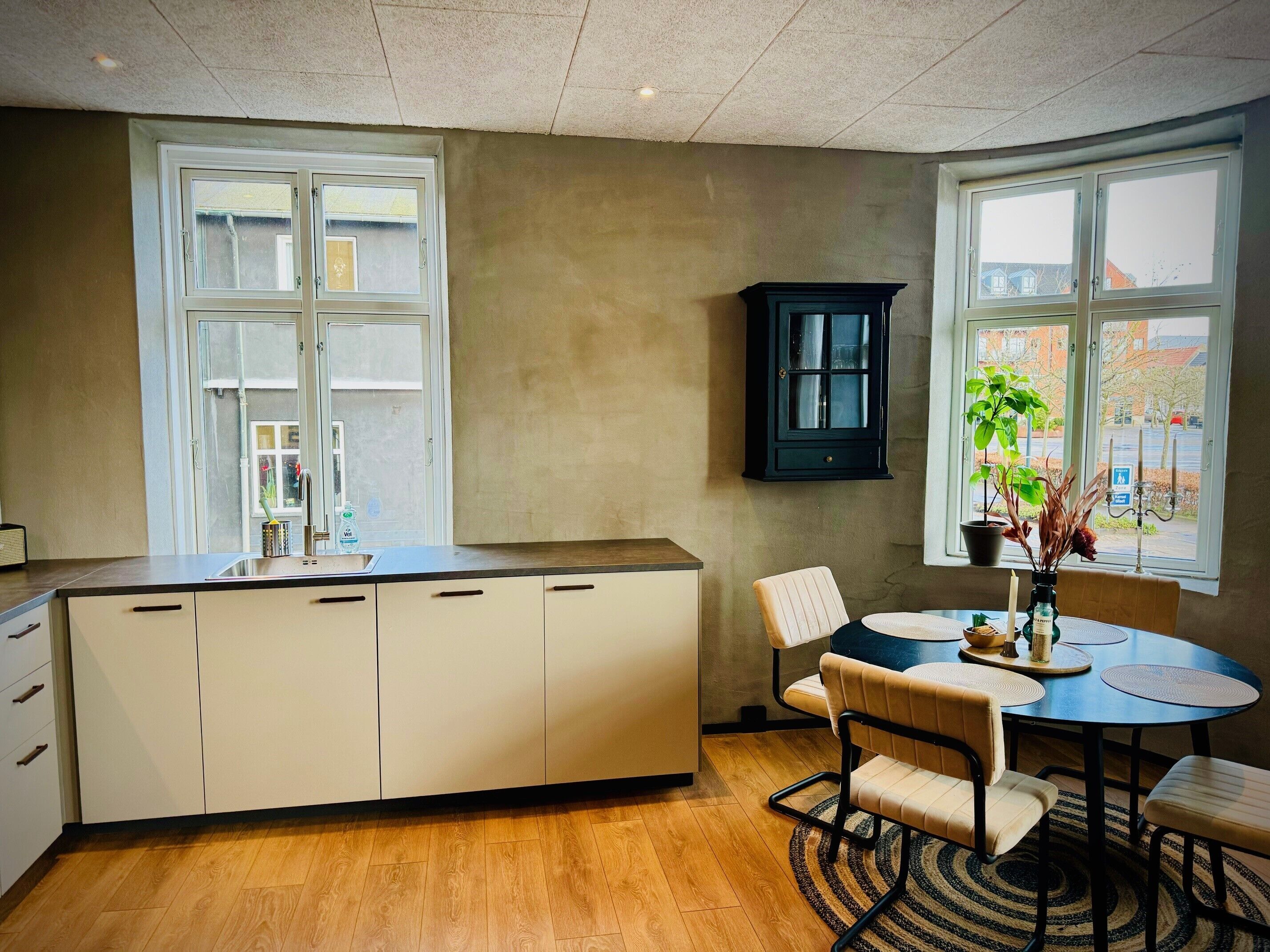 Une cuisine moderne dotée d’un îlot central, de meubles blancs et d’une fenêtre donnant sur l’extérieur.