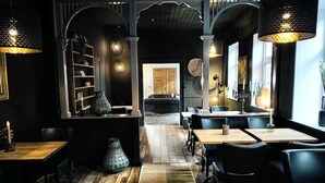 A restaurant interior with wooden flooring, black leather seating, and decorative lighting. - Hotel Gammel Havn - Good Night Sleep Tight (Fredericia)