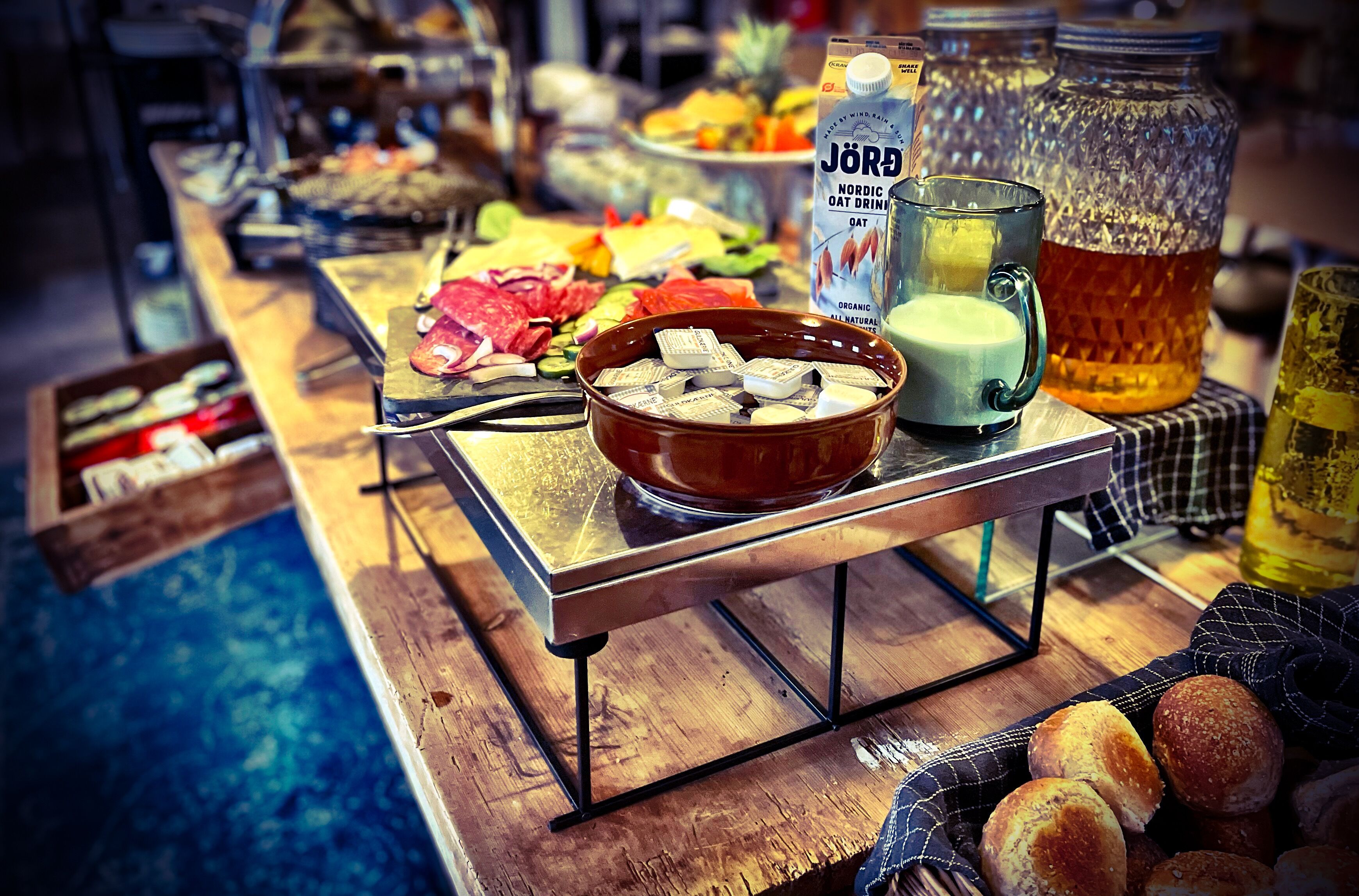 A buffet table with various food items, a bowl of cheese, a milk carton, and a honey jar.