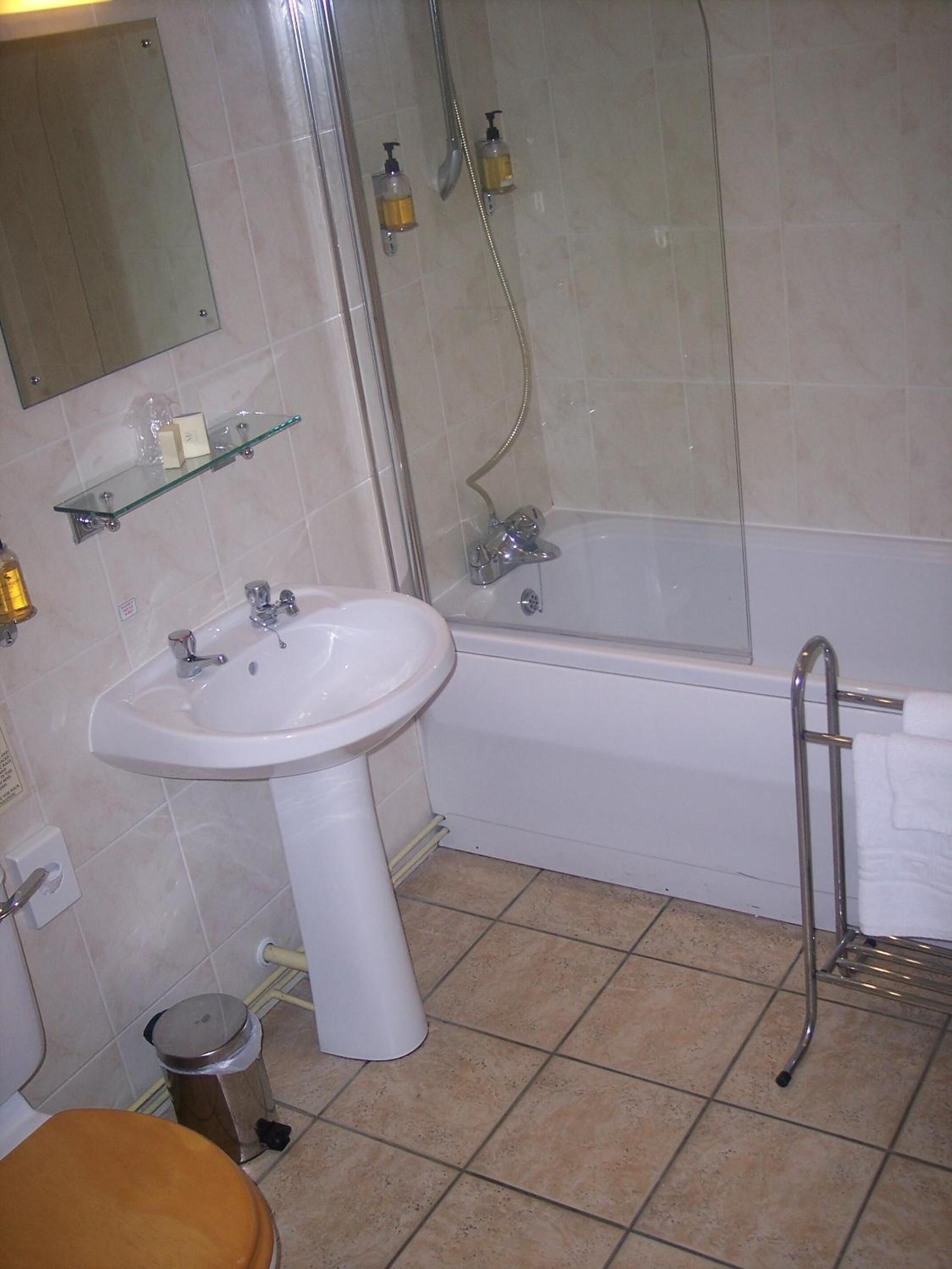 Un baño con lavamanos, espejo, ducha e inodoro.
