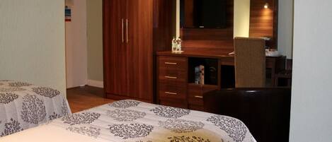 Habitación de hotel con cama, escritorio con silla, armario y televisor.