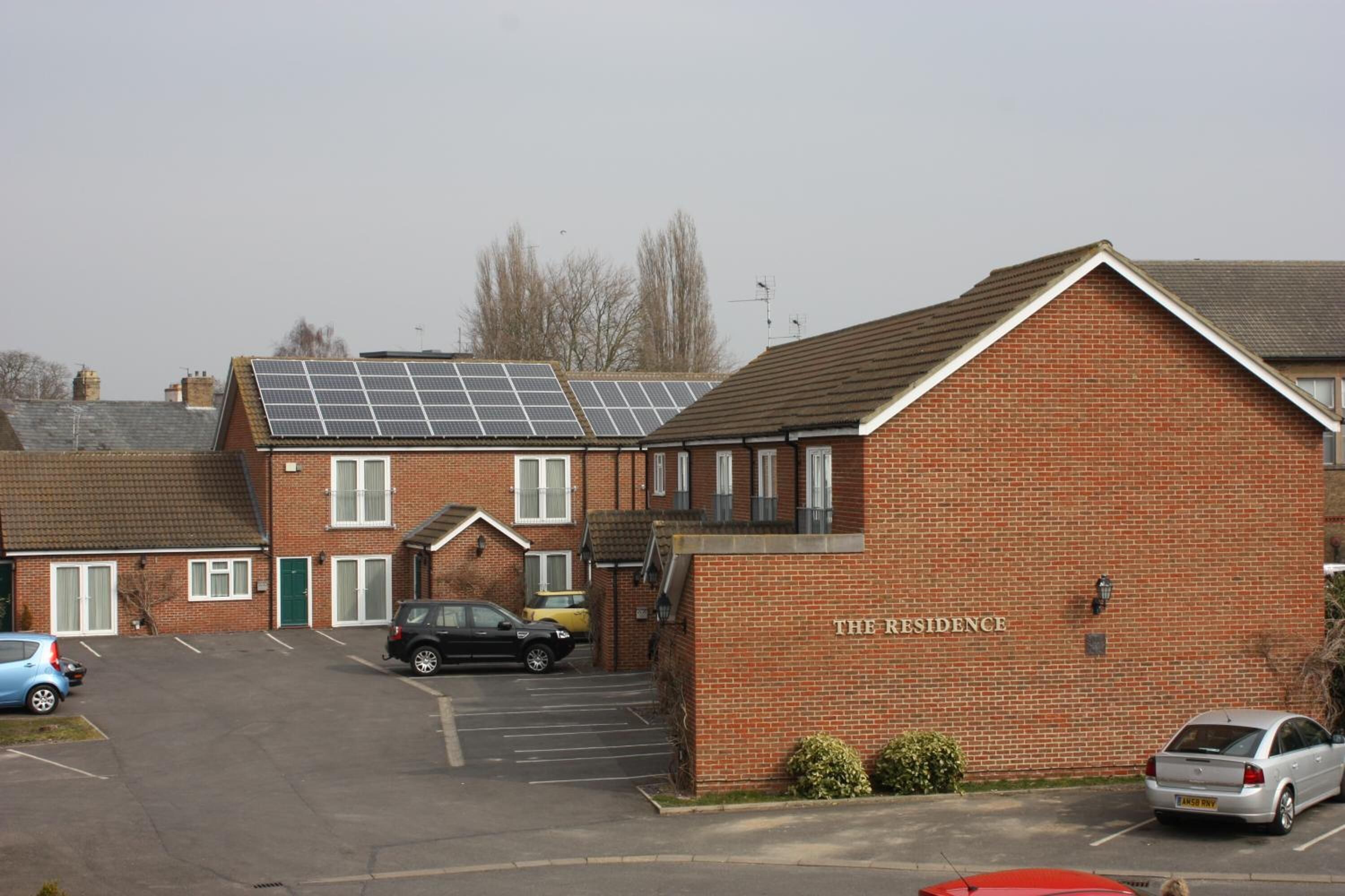 Ein Backsteinhaus mit Solaranlage auf dem Dach, beschriftet mit „THE RESIDENCE“.
