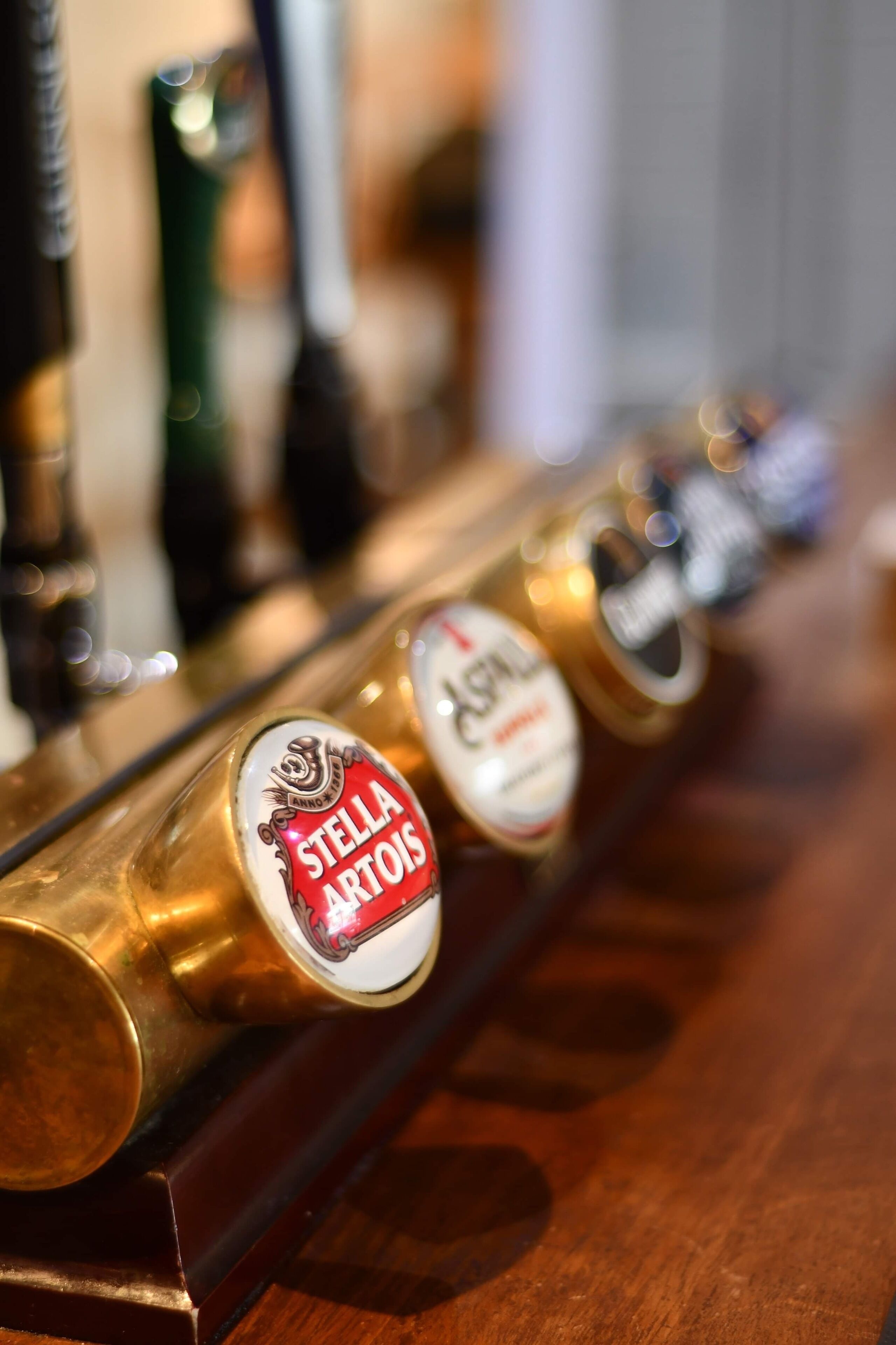 Una hilera de grifos de cerveza con etiquetas, incluyendo uno de Stella Artois.
