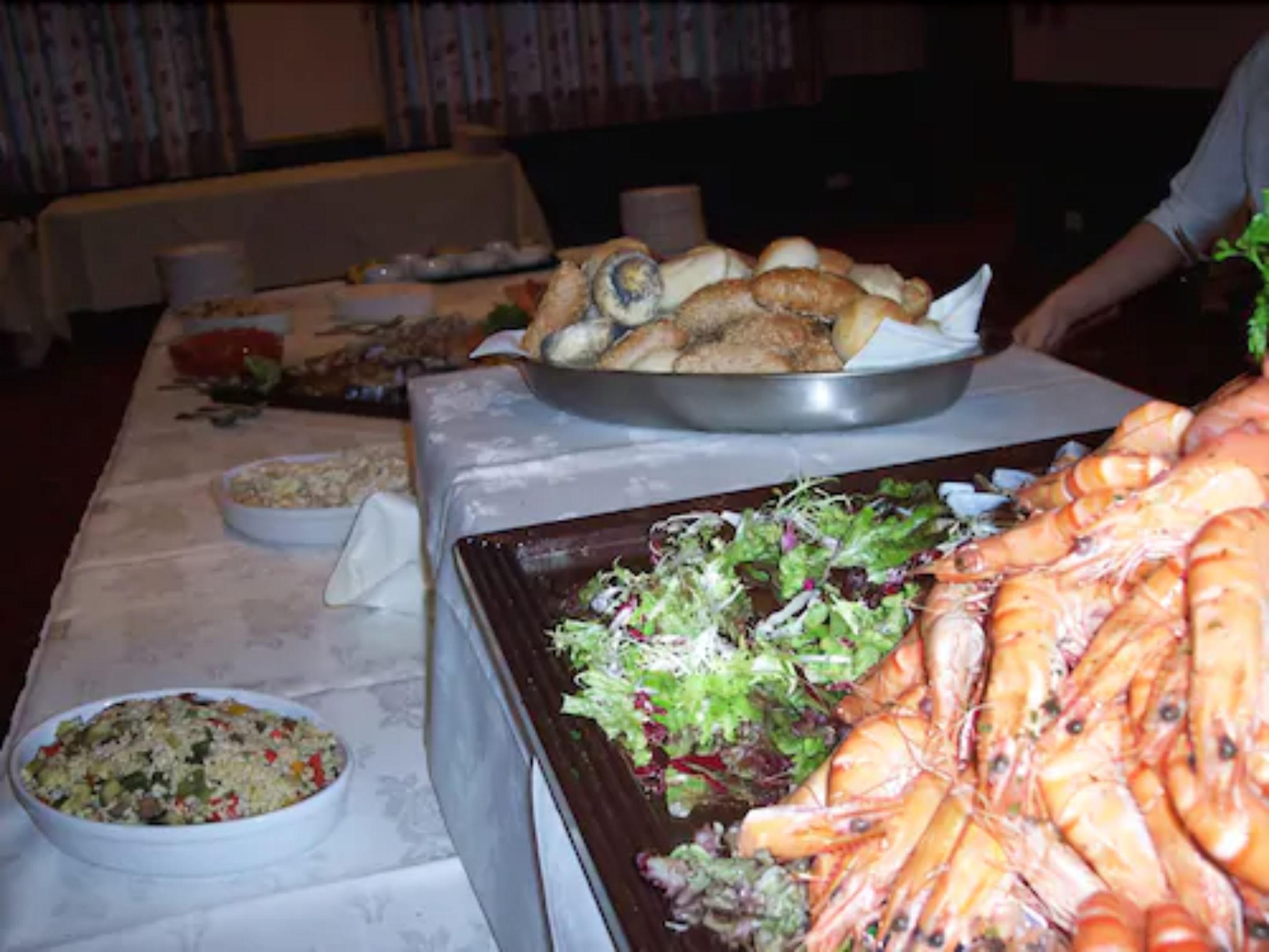 Una mesa de comedor con diversos platos, incluyendo camarones, ensalada y otros alimentos.