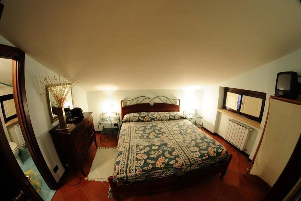Une chambre à coucher comprenant un lit, des tables de chevet, une commode, un radiateur et un téléviseur.