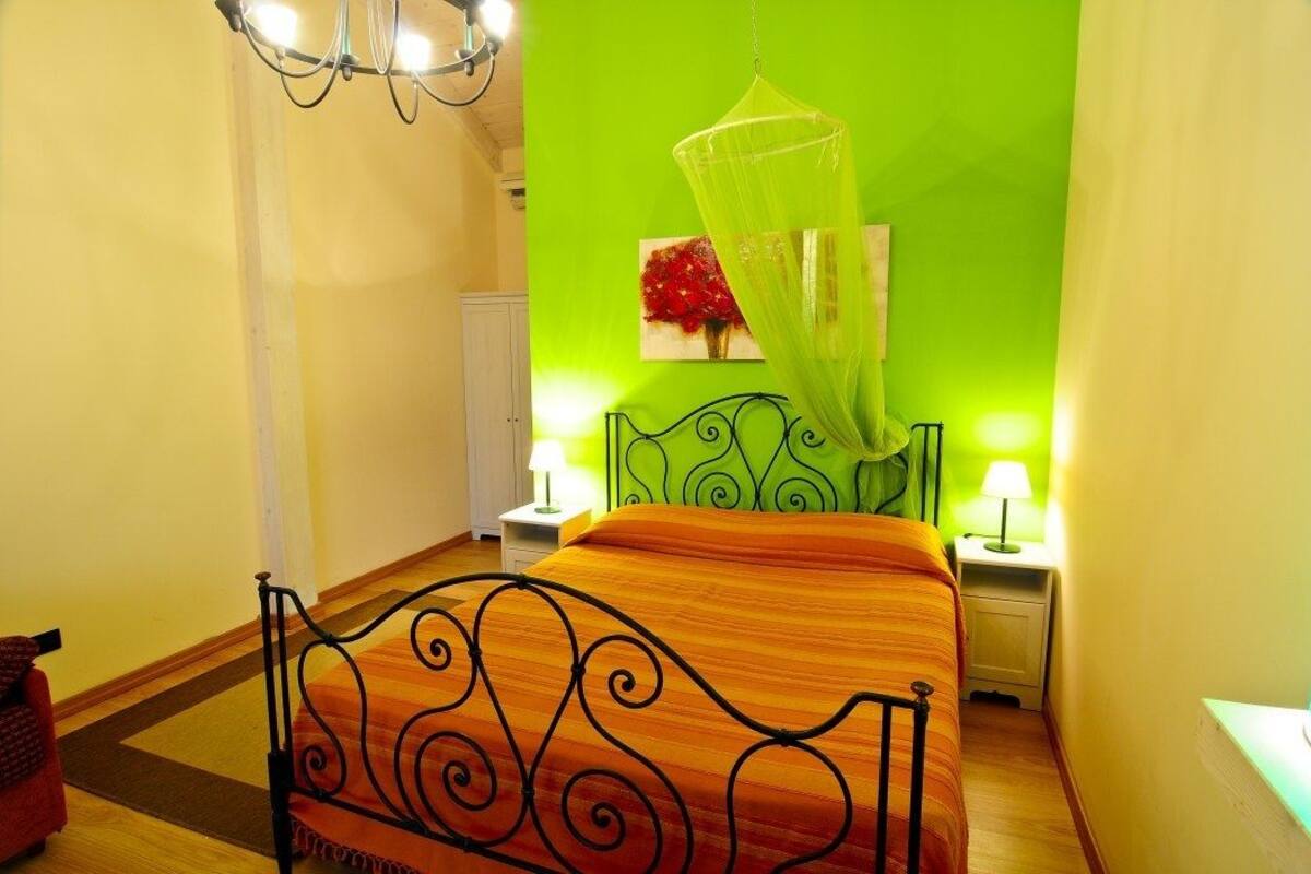 Une chambre avec un lit, des lampes de chevet, une moustiquaire suspendue et un tableau au mur.