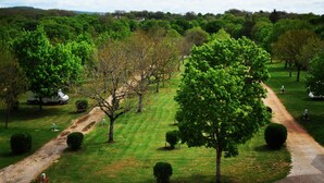 A park with a dirt path, green grass, and trees. - Amadour Hôtel (Rocamadour)