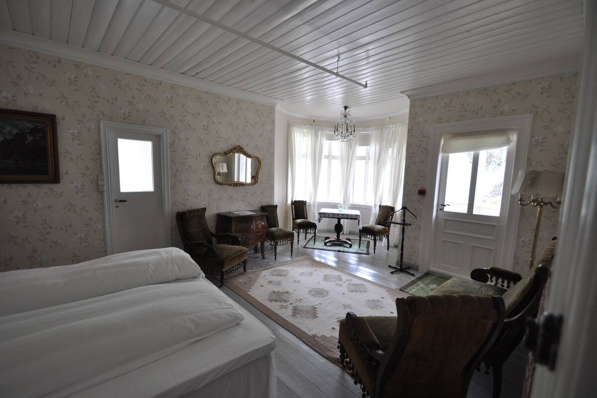 A room with a bed, a table, chairs, a mirror, and a chandelier.