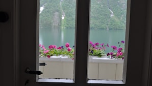 A door with two windows, each with a white frame and a view of a lake and greenery. - Hotel Mundal (Sogndal)