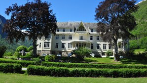 A large, multi-story building with a symmetrical facade, surrounded by well-manicured gardens and trees. - Hotel Mundal (Sogndal)