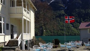 A building with a porch and outdoor seating area with chairs and tables. - Hotel Mundal (Sogndal)