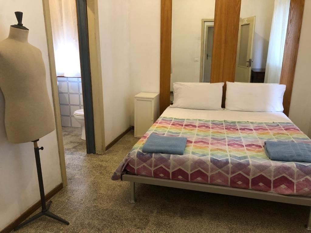 Un dormitorio con cama, mesita de noche, espejo y un maniquí.