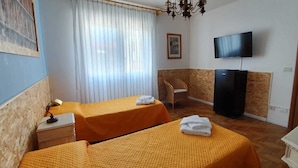 Une chambre d’hôtel avec deux lits, une télévision, une chaise et un bureau.