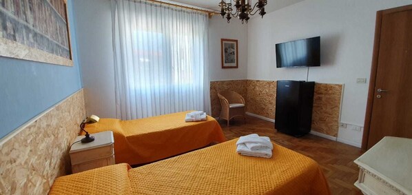 Una habitación de hotel con dos camas, televisión, una silla y un escritorio.