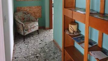 Un corridoio con una poltrona floreale, una libreria in legno e un pavimento piastrellato.