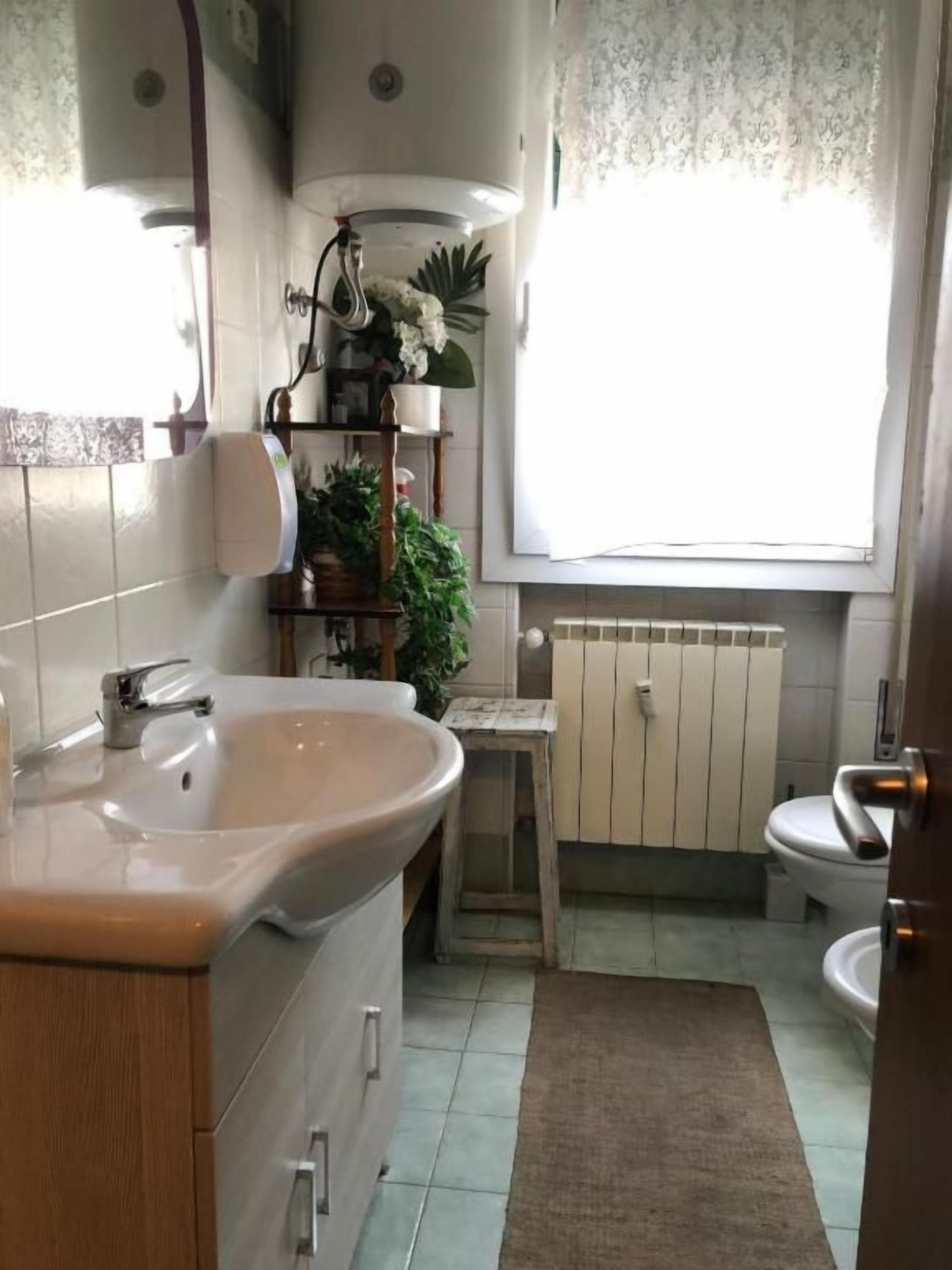 A bathroom with a sink, toilet, and window.