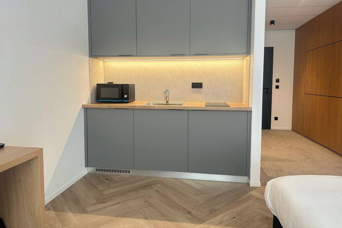 A compact kitchenette with a microwave, sink, and cabinets.