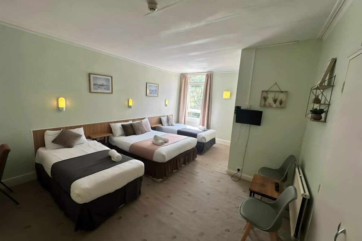 A hotel room with two beds, a desk, and a chair.