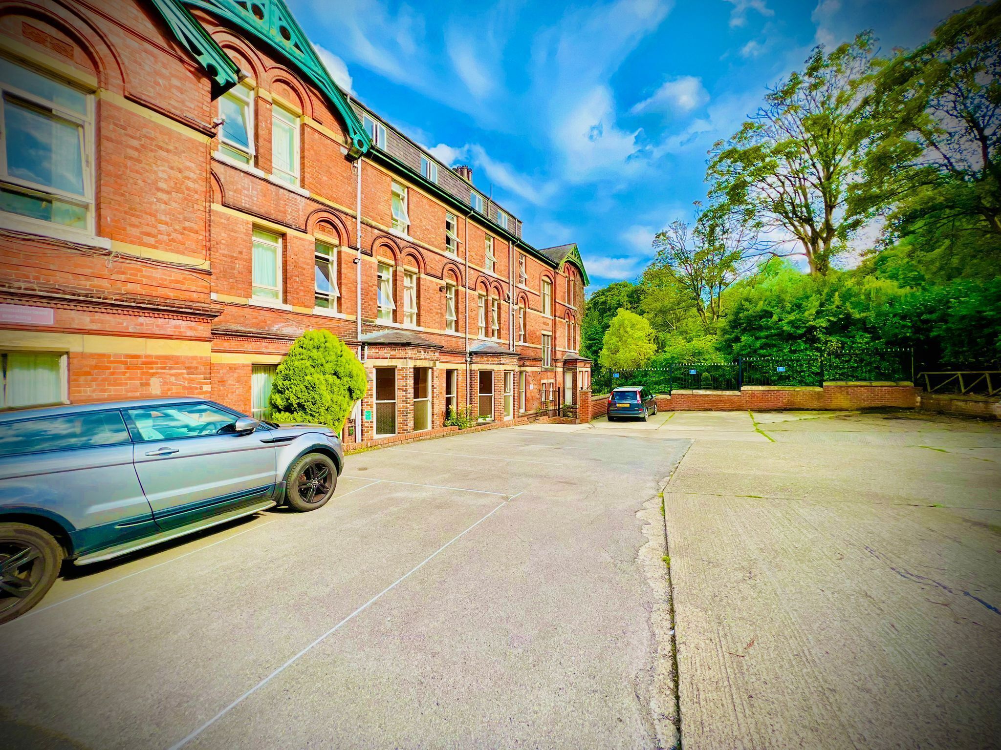A building with a brick facade, a car parked in front, and a tree to the right.