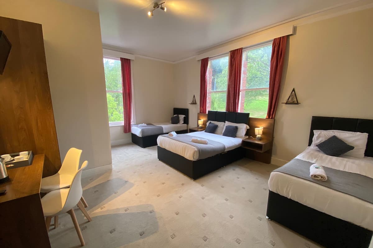 A hotel room with two beds, a desk, and a chair.