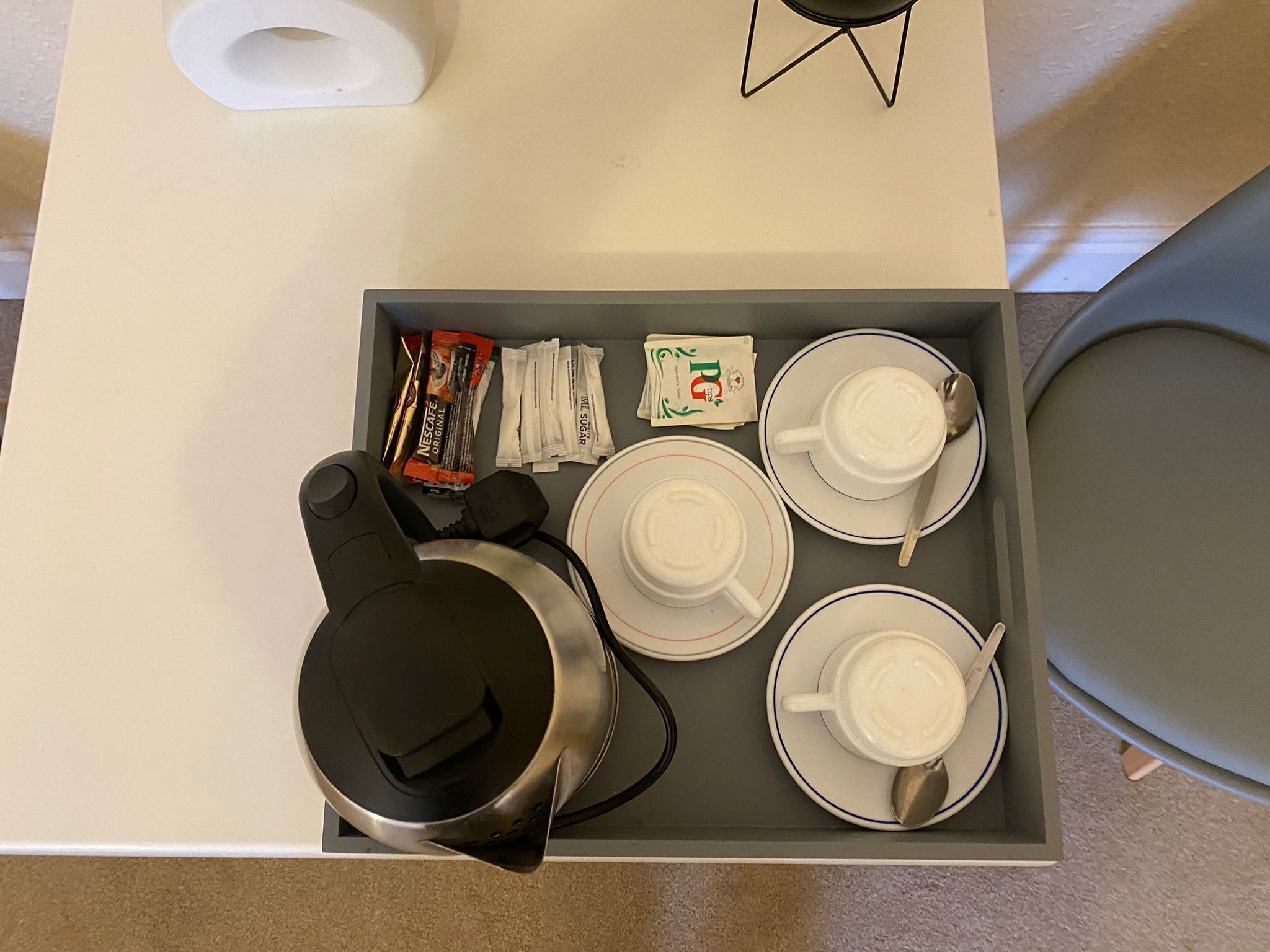 Una bandeja con una cafetera, cuatro tazas y cápsulas de café sobre una mesa.