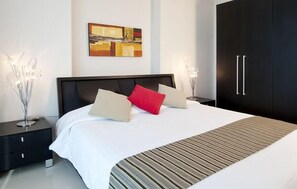 Une chambre à coucher moderne avec un grand lit, une armoire noire et un tableau accroché au mur.